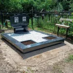 Памятник с крестом, ограда и цветы — фото 2