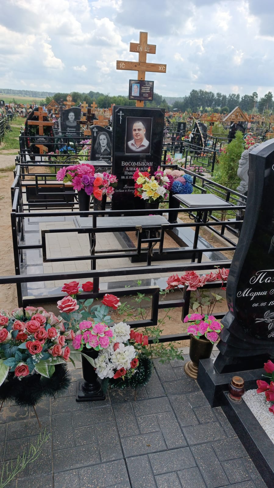 Памятник с крестом, ограда и цветы